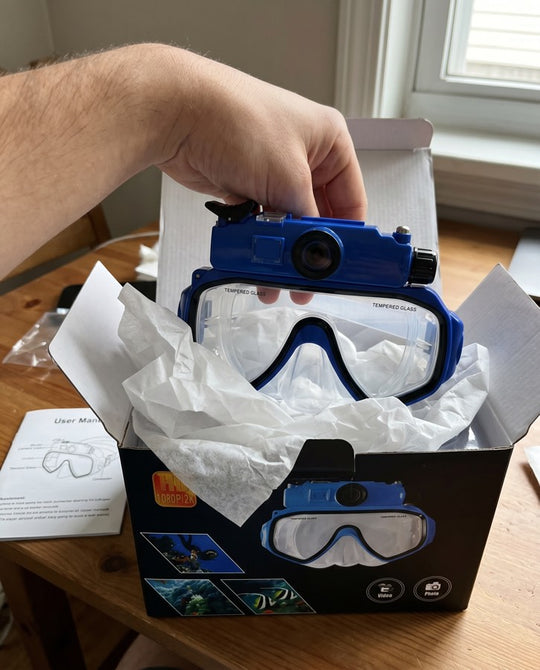 Hands lifting the blue Deep Dive Goggles out of its box