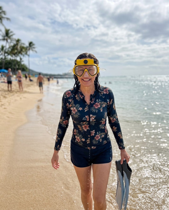Woman walking the beach with the yellow mask and fins