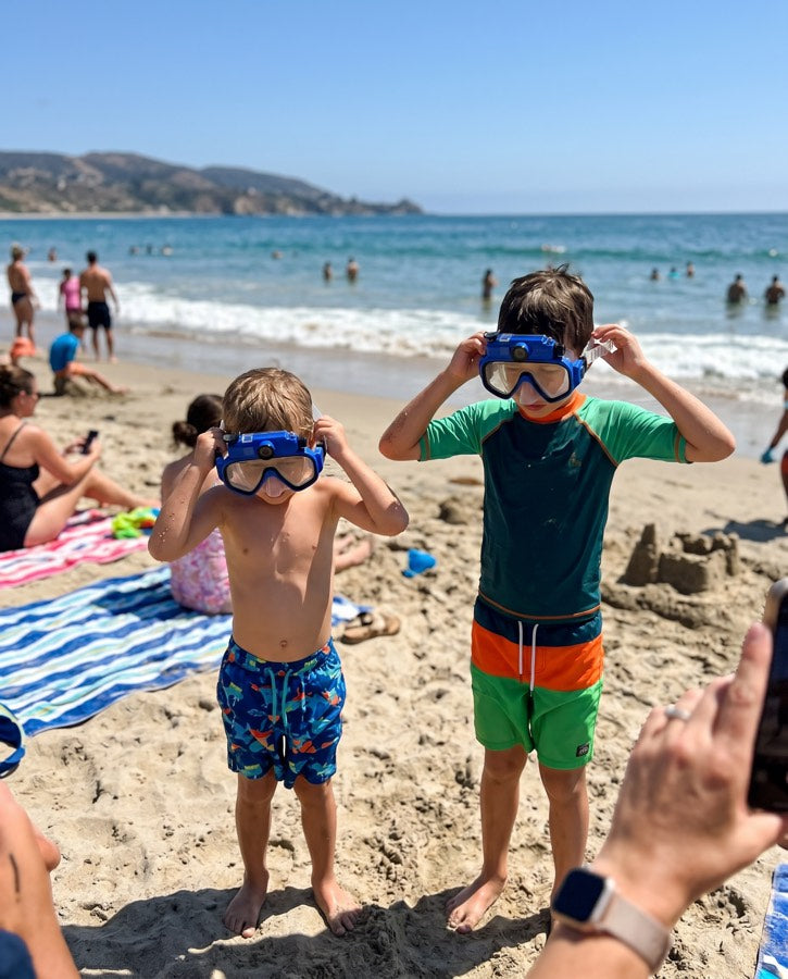 Two boys putting on their masks at the beach
