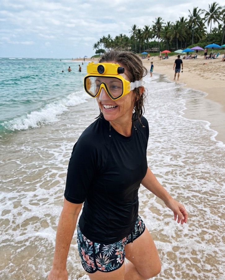 Woman on the beach wearing the yellow mask, smiling