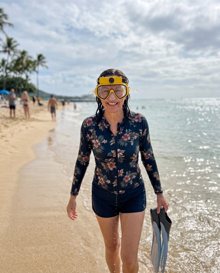 Woman walking the beach with the yellow mask and fins